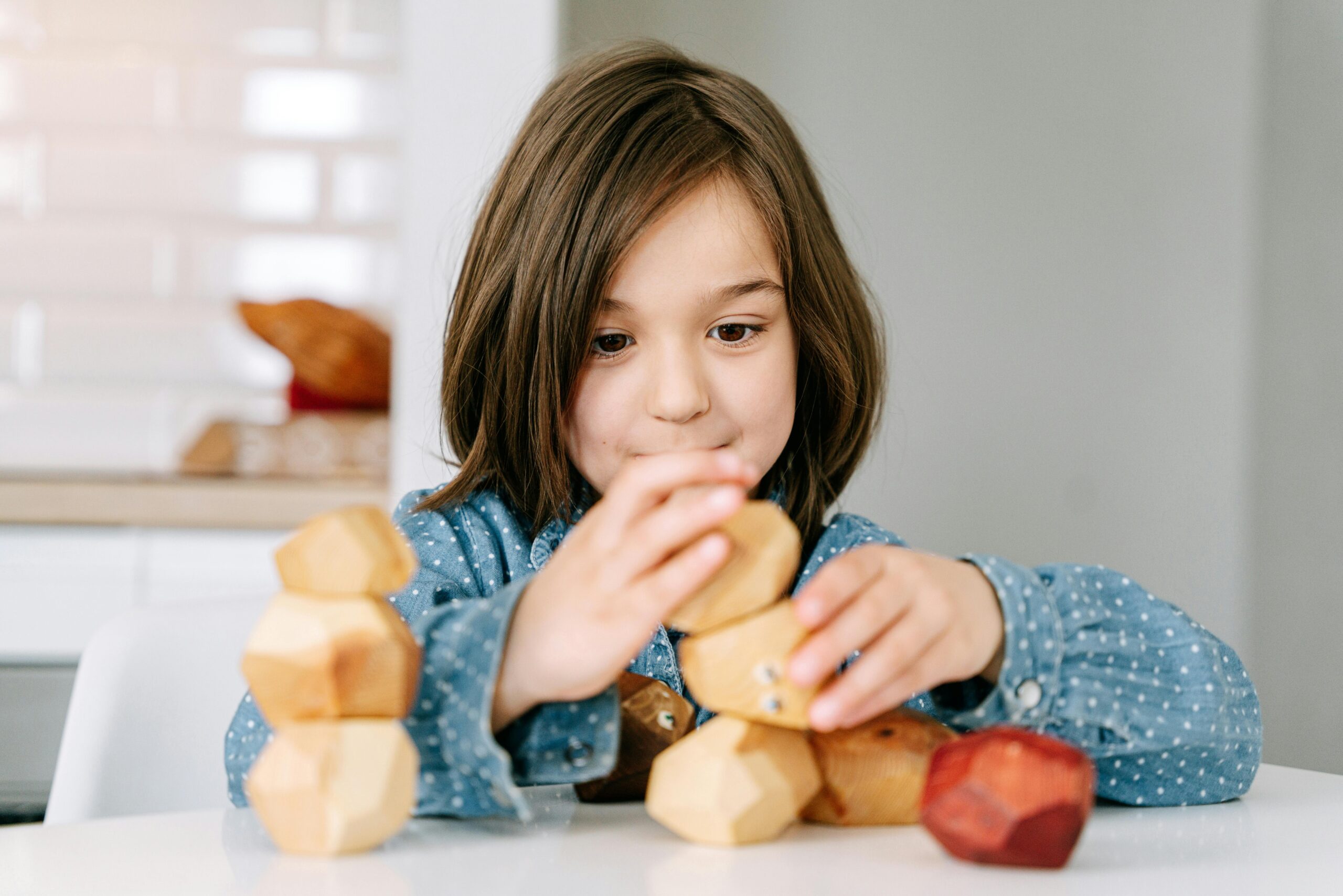 Child playing with wooden blocks indoors, focusing on playful and educational activity.